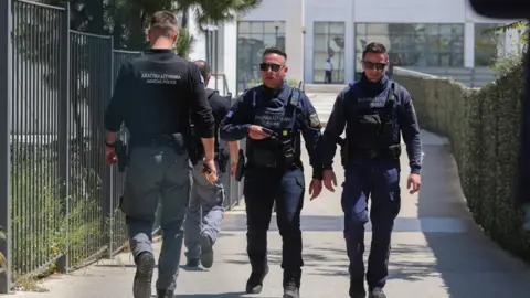 Reuters Three police officers walk outside a courthouse in following a shooting incident that left several wounded. The men wear dark navy uniforms, bullet proof vests and sunglasses.