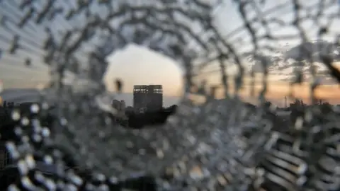 Reuters A building seen through shattered glass caused by artillery in Shire.