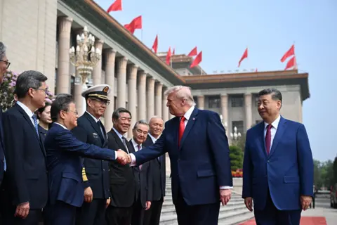 Getty Images U.S. President Donald Trump trailed by Chinese President Xi Jinping greets other officials at the Great Hall of the People on May 14, 2026 in Beijing, China