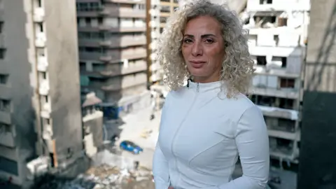 Woman stands on balcony overlooking a bomb site