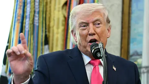 AFP via Getty Images US President Donald Trump speaks into a microphone from the Oval Office. Photo: 24 March 2026. 