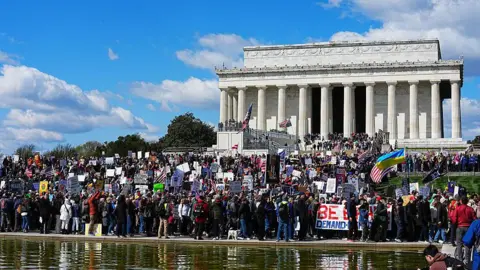 Getty Images Hundreds of protestors gather in front of the Lincoln Memorial in Washington DC, holding signs and waving flags