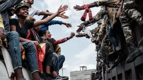 AFP via Getty Images TPLF supports on a bus reach out to touch hands with Tigray soldiers in Mekelle, Tigray - 2021