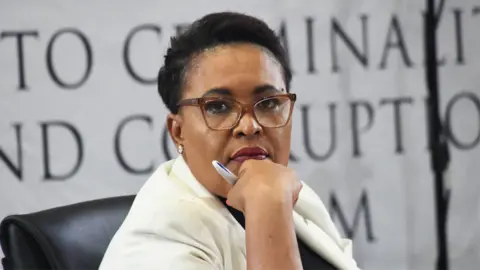 Gallo Images via Getty Images Brigadier Rachel Matjeng, wearing glasses and in a cream blazer, testifies at Madlanga Commission in Pretoria on 6 February 2026.