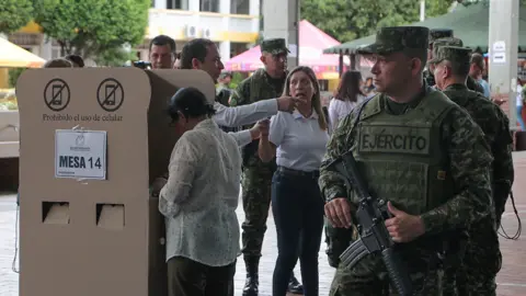 EPA A person casts a ballot as members of the Colombian Army stand guard at a polling station during the presidential election in Cucuta.