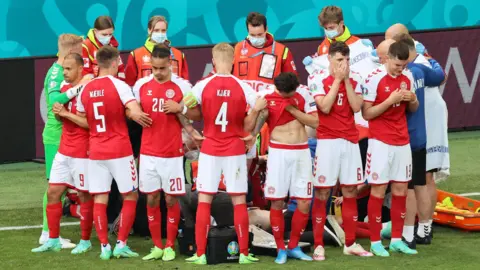 Reuters Players from Denmark form a collective ring to shield their teammate Christian Eriksen as he receives medical assistance during the UEFA EURO 2020 Group B match between Denmark and Finland in Copenhagen, Denmark, on 12 June 2021.