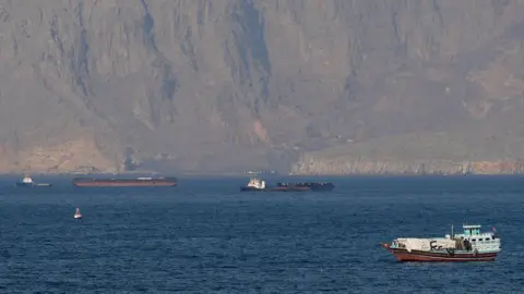 Reuters Ships and tankers sit in the water with high cliffs in the background