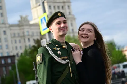 Anadolu via Getty Images A Russian soldier poses for a photo with a woman in Moscow's Red Square.