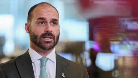 Reuters Brazilian lawmaker Eduardo Bolsonaro sits down, wearing a dark suit and blue tie
