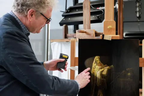 Kelly Schenk, Rijksmuseum A researcher points at, and points a torch at, the figure of Zacharias from Rembrandt’s Vision of Zacharias in the Temple (1633), which is on an easel