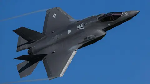 Getty Images A black F-35 Lightning II stealth fighter jet turns through a clear blue sky.