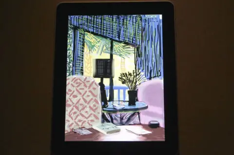Getty Images David Hockney artwork on an iPad. The painting is of a room with blue walls and red chairs. It is a still life.