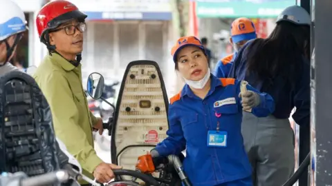 EPA/Shutterstock An employee pumps fuel into a customer's motorbike at a petrol station in Hanoi, Vietnam