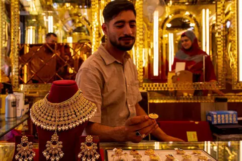LightRocket via Getty Images) Goldsmith Sahil Bilal arranges gold necklaces and earrings displayed for sale at a jewelry shop in Srinagar, Indian-administered Kashmir. 