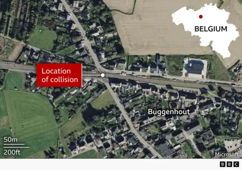 Aerial satellite view of Buggenhout, Belgium, showing a railway line running through a residential area with houses, roads, and surrounding fields. A white dot marks a level crossing on the tracks, highlighted by a red label reading “Location of collision.” An inset map in the top right shows Belgium with a red dot marking the town’s position.