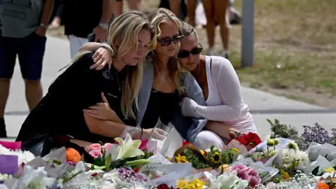 Getty Three women with blonde hair look at floral tributes