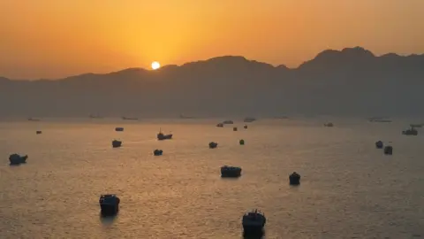 Reuters Ships anchored in the Strait of Hormuz at dusk 