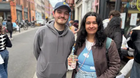 A young man and a young woman smile at the camera