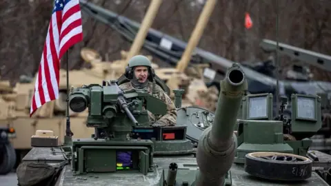 EPA-EFE/REX/Shutterstock A US soldier rides on a tank in Grafenwoehr, Germany. Photo: February 2025