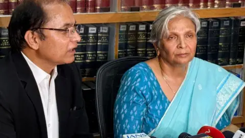 Vishnukant Tiwari/BBC Hindi Retired judge Giribala Singh seen in a blue sari - a lawyer is seated next to her in his black and white uniform