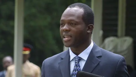 AFP via Getty Images Raphael Tuju in a dark blue suit and light blue shirt