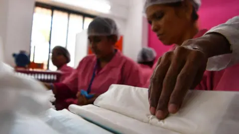 AFP via Getty Images Indian employees at the Myna Mahila Foundation prepare sanitary pads at their office in Mumbai on April 10, 2018.