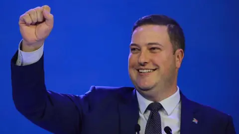 Gallo via Getty Images Geordin Hill-Lewis is seen with his fist raised after his election as the DA's new leader