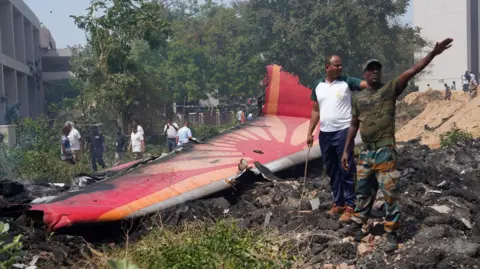 EPA People stand near debris at the site of a plane crash near Sardar Vallabhbhai Patel International Airport in Ahmedabad, Gujarat, western India, 12 June 2025. Air India flight AI171, bound for London carrying 242 passengers and crew members on board a Boeing 787-8 aircraft, crashed minutes after take-off in the Meghaninagar area of Ahmedabad.
Air India plane with over 240 on board crashes after take-off in Ahmedabad - 12 Ju
