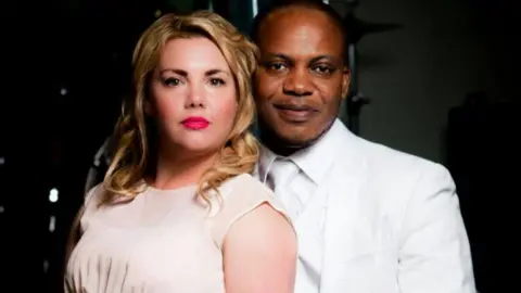 Facebook Charmain and Eric - Woman in a light dress and man in a white suit posing together in a studio-style portrait.