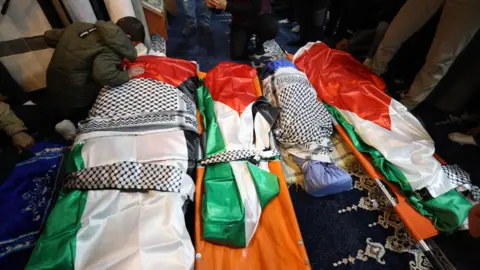 EPA One of the two surviving children of the Bani Odeh family mourns next to his parents' and brothers' bodies during their funeral in Tammun, in the Israeli-occupied West Bank (15 March 2026)