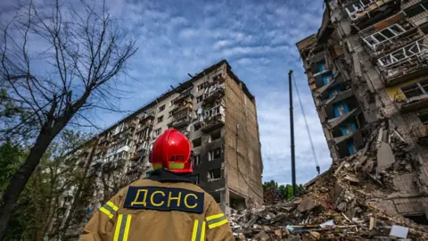 Getty Images Rescue workers operate at the site of a Russian missile strike on a nine-story residential building, on 17 June 2025 in Kyiv, Ukraine. 