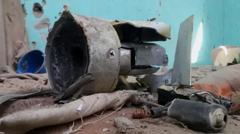 Reuters Remnants of a shell inside a refugee centre in el-Fasher. The wall behind it is blue and damaged and the floor is covered in debris