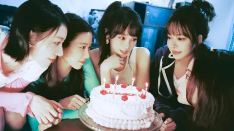 Source Music Le Sserafim gather around a birthday cake in a promotional image for their single, Celebration