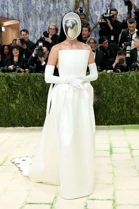 Getty Images Katy Perry wears a white gown. Her face is obscured by a mirrored headpiece.