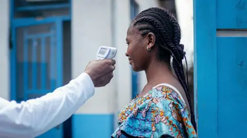 AFP via Getty Images A staff member of the CBCA Virunga Hospital checks a visitor's temperature using a a contactless infrared thermometer, before allowing her access to the hospital in Goma on May 17, 2026