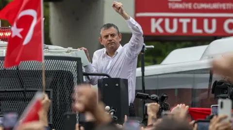 Getty Images Ousted CHP leader Özgür Özel waves to supporters atop a police water cannon vehicle