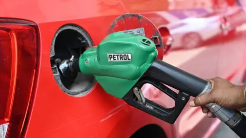 Hindustan Times via Getty Images A worker fills a red car with fuel with a green pump labelled petrol on 23 May, 2026 in New Delhi, India.