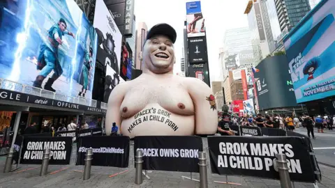 Getty Images An inflatable balloon in New York City's Times Square designed to resemble Elon Musk has the words "SpaceX's Grok makes AI child porn" tattooed across its chest. 