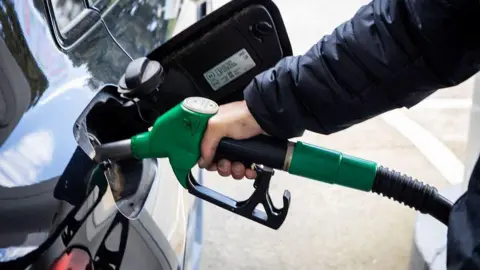 AFP via Getty Images Fuel nozzle inserted into a vehicle tank at a service station illustrating fuel consumption and everyday energy use in Sartene South Corsica France on March 20, 2026