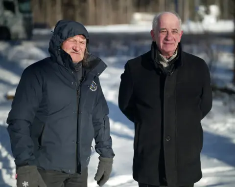 Rein Klaar (left) and Jaan Krinal (right) pictured in Estonia. They are wearing dark-coloured winter coats against a backdrop of snow. Rein has his hood up and is wearing heavy gloves.