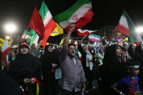 Anadolu via Getty Images Citizens, carrying Iranian and Hezbollah flags, gather at Enghelab Square in Tehran, Iran, to hold a demonstration in support of the government following Iran's missile attack on Israel, on 8 June 2026.