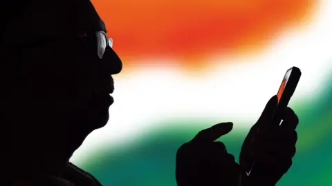 Getty Images Silhouette of a senior Indian man using an mobile app - stock photo. 