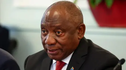 Reuters A head-and-shoulders shot of Cyril Ramaphosa. He is wearing a dark jacket and red tie.