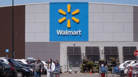 Getty Images Shoppers walk through the car park after leaving a Walmart grocery store.