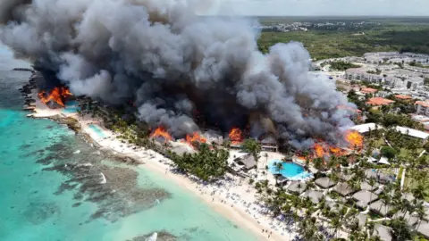 Reuters Drone shot of the a large dark cloud of smoke and flames over the Viva Wyndham Dominicus Beach.