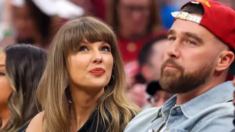 Getty Images Singer Taylor Swift tilts her head up while sitting next to fiance Travis Kelce of the Kansas City Chiefs at Game Three between the New York Knicks and the Cleveland Cavaliers in the NBA Eastern Conference Finals.