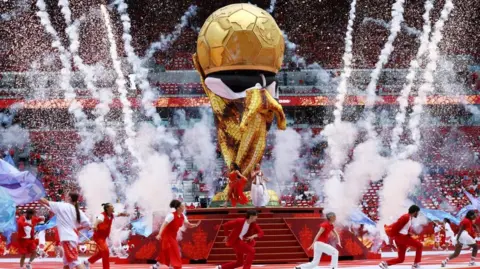 Reuters Singers Elyanna and Jessie Reyez perform during the opening ceremony. They are on a stage with a replica gold world cup and are dressed in colourful clothing