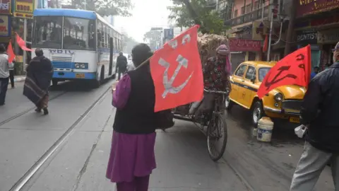 AFP via Getty Images Communist Party of India (CPI) activists stop vehicles along a road during a nationwide strike against new labour policies introduced by India's central government, in Kolkata.