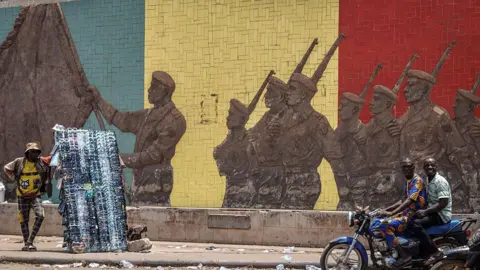 AFP via Getty Images A motorcyclist rides past a monument in support of the Malian Army in Bamako on April 26, 2026. 