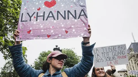 AFP via Getty Images A woman holds up a sign saying